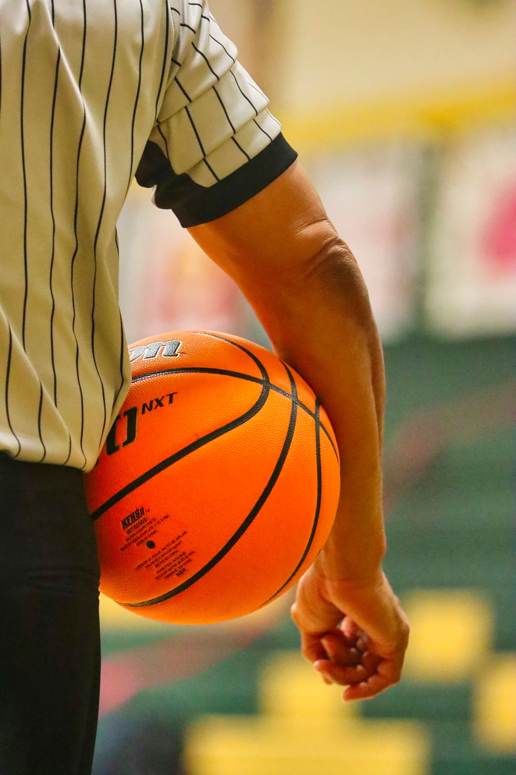 Close view of a basketball held at a player's side.